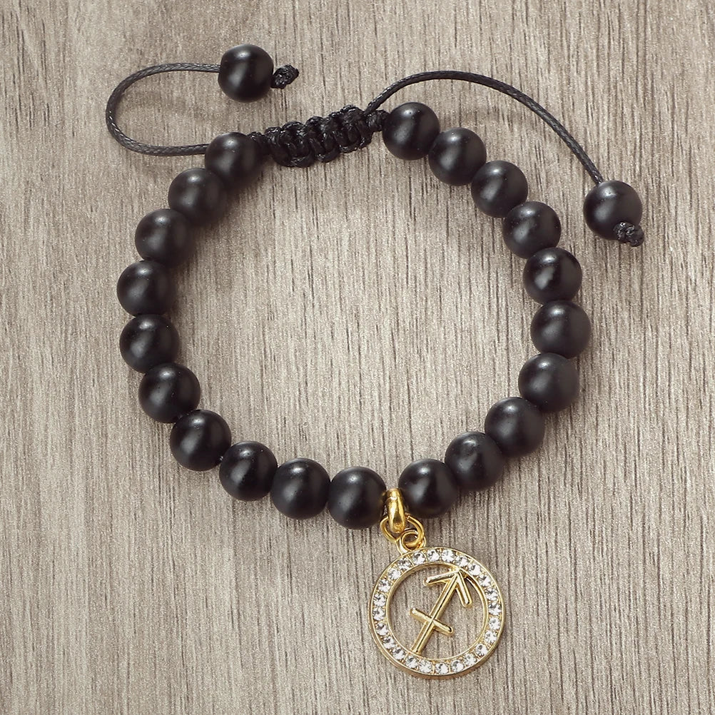 A handmade beaded bracelet with natural black stones and a gold zodiac charm