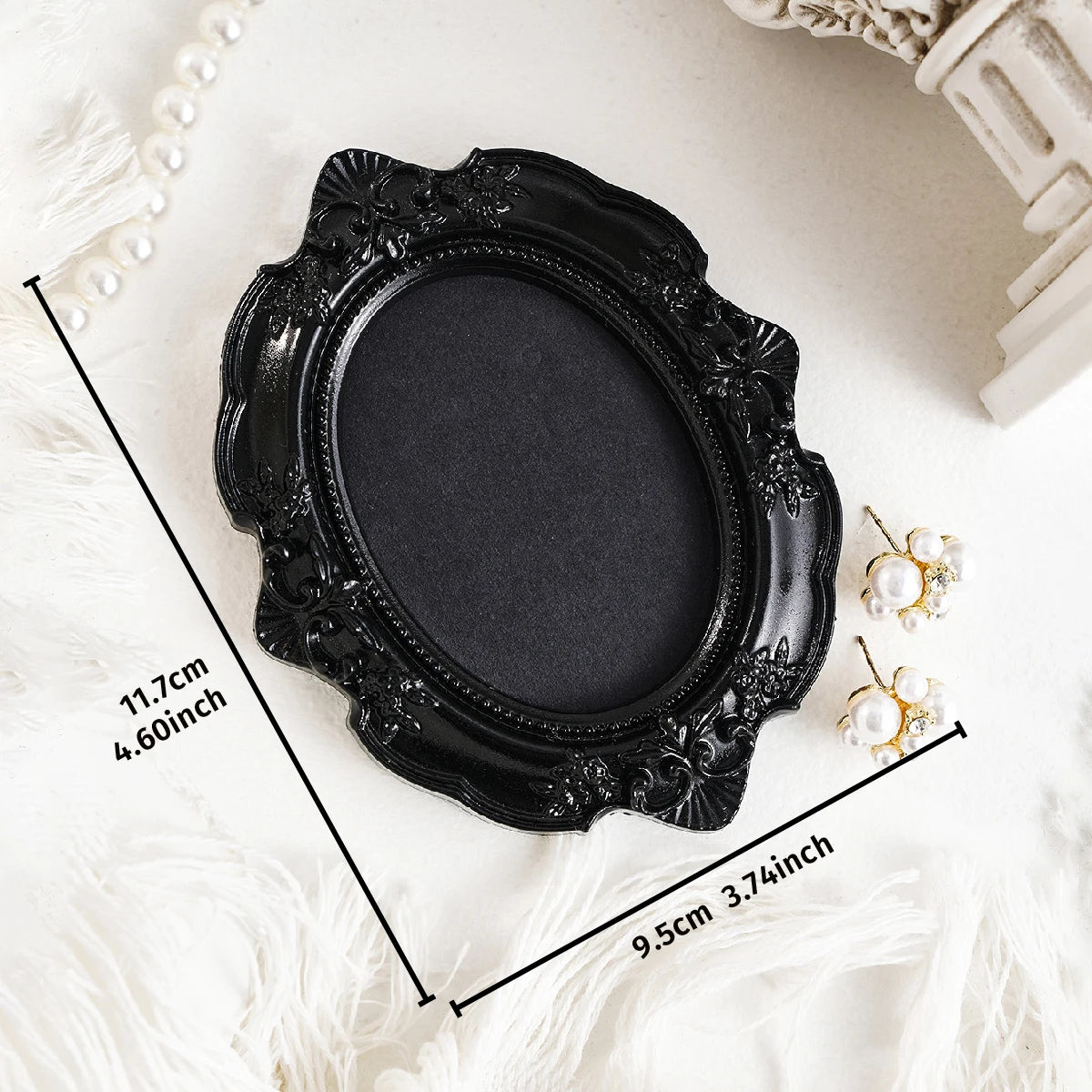 Black ornate oval frame wall decor pendant with pearl accents shown on a white surface.