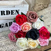 A bouquet of artificial roses in shades of red, pink, and white arranged on a wooden surface.