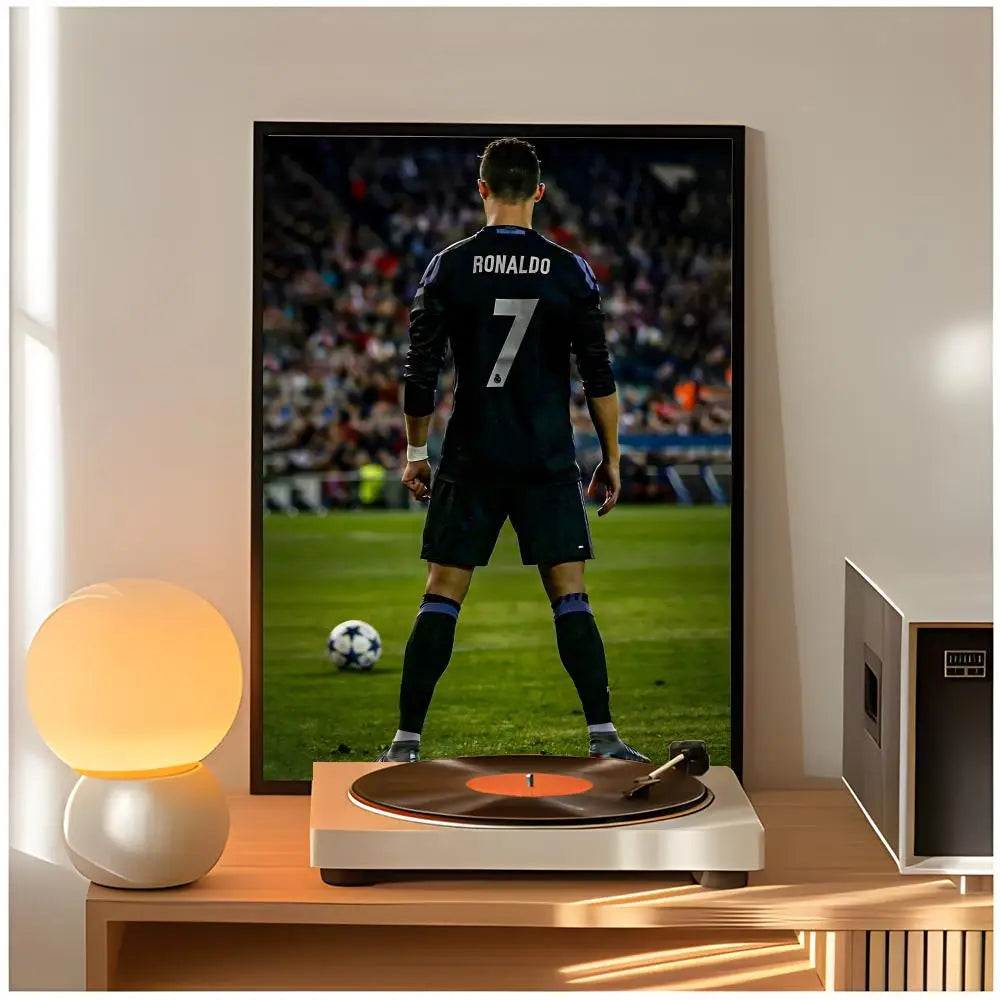 A framed poster of Cristiano Ronaldo in a dark jersey standing on a soccer field, displayed next to a pool table.