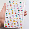 A hand holds a sheet of glitter gem stick-on facial tattoos featuring various colored gemstones.