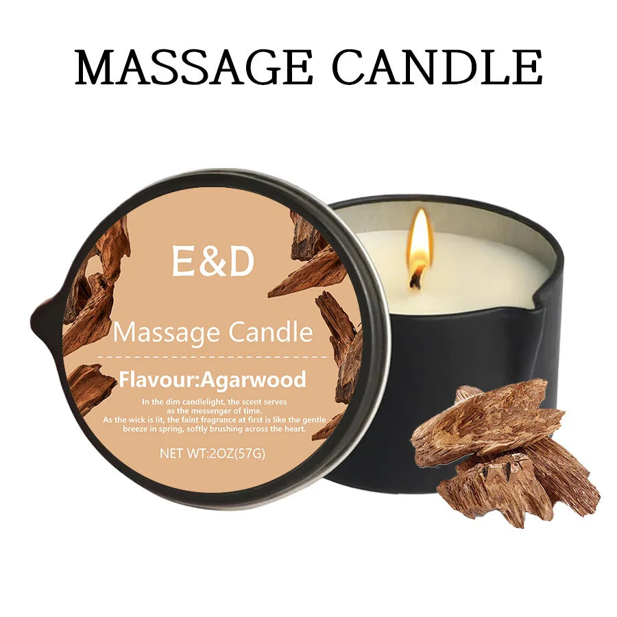 A dark candle in a black holder with a lit wick, showing the label for an E&D Massage Candle with Agarwood flavour.