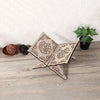 Handcrafted wooden Quran book stand with intricate Arabesque design resting on a wooden surface next to a potted plant.