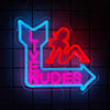 Neon wall sign featuring a silhouette of a woman and the word NUDES in bright pink and blue neon tubing.