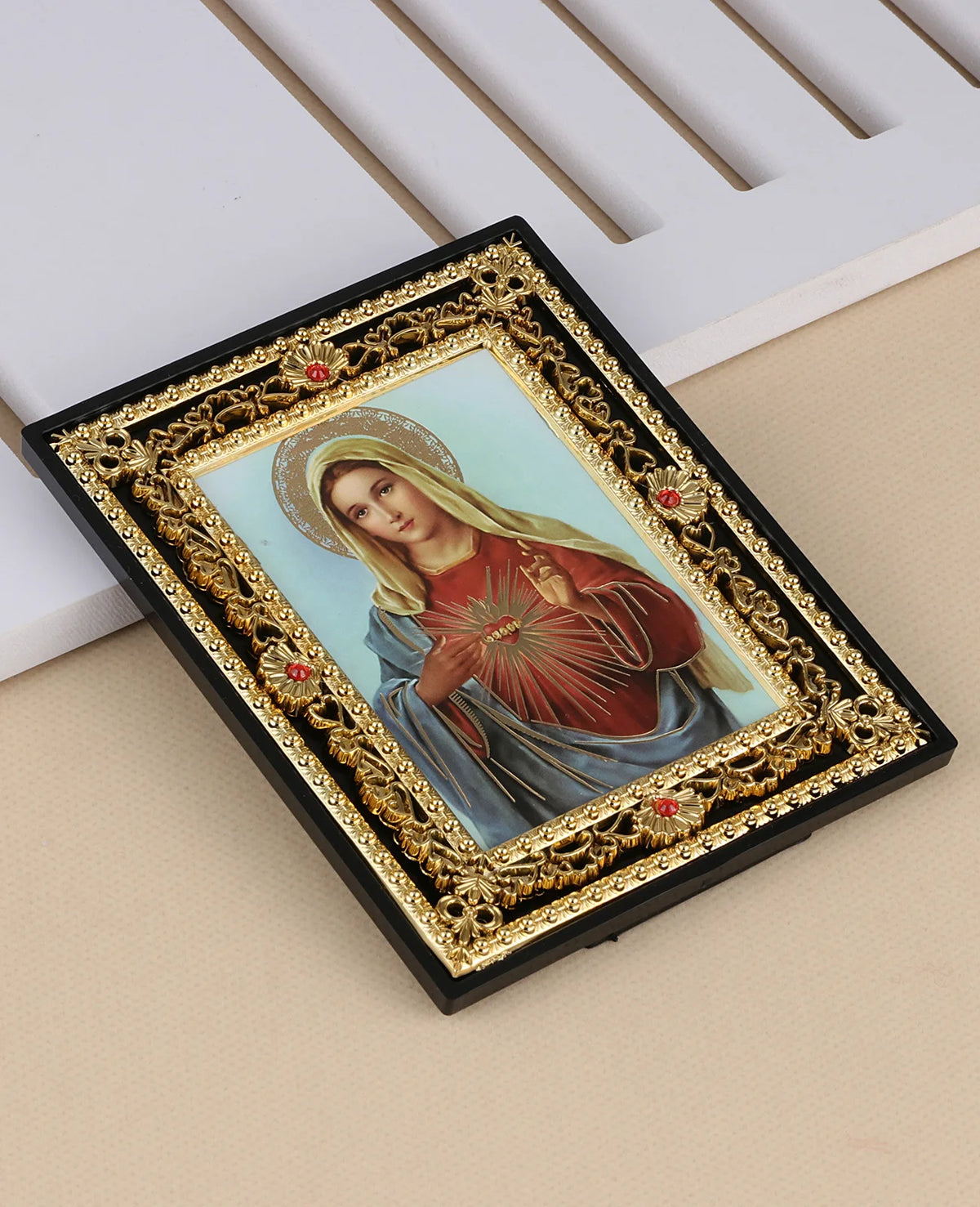 A framed icon of the Virgin Mary with a halo and St. Michael, featuring gold detailing on a black frame.