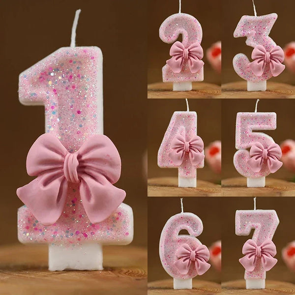 A set of pink glitter number candles featuring various digits, including 1 through 7, with decorative pink bows.