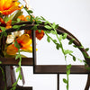 Artificial green climbing vine with orange and yellow flowers decorating a dark wooden chair frame