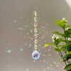 A long, delicate crystal prism necklace with multiple facets and rainbow reflections hanging against a light background.