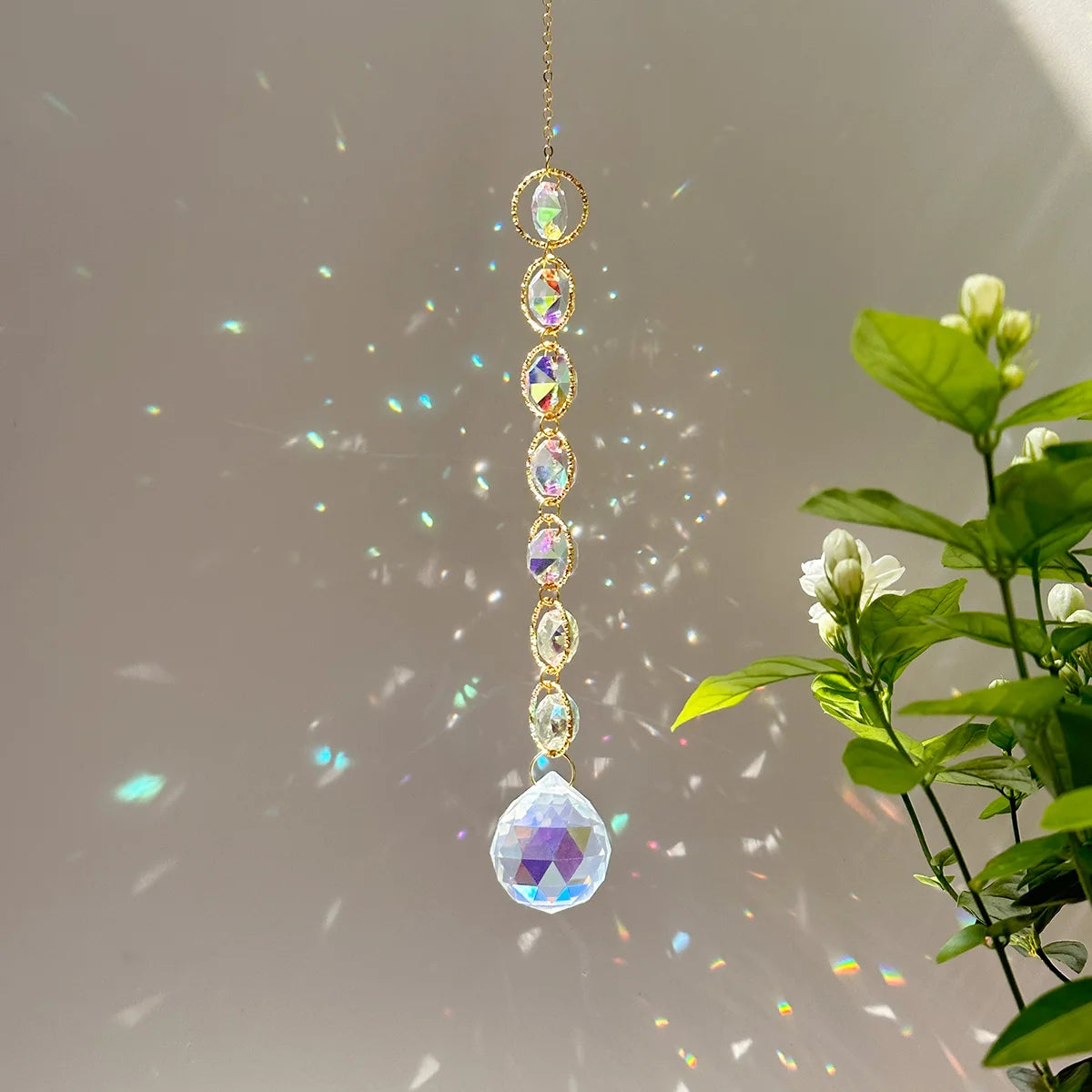 A long, delicate crystal prism necklace with multiple facets and rainbow reflections hanging against a light background.