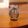 A clear glass miniature dollhouse vase and wine bottle set sitting on a wooden surface.