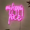 Pink neon sign spelling out My Happy Place mounted on a white wall.