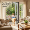A woman and a dog walk through a glass magnetic automatic screen door in a bright living room.