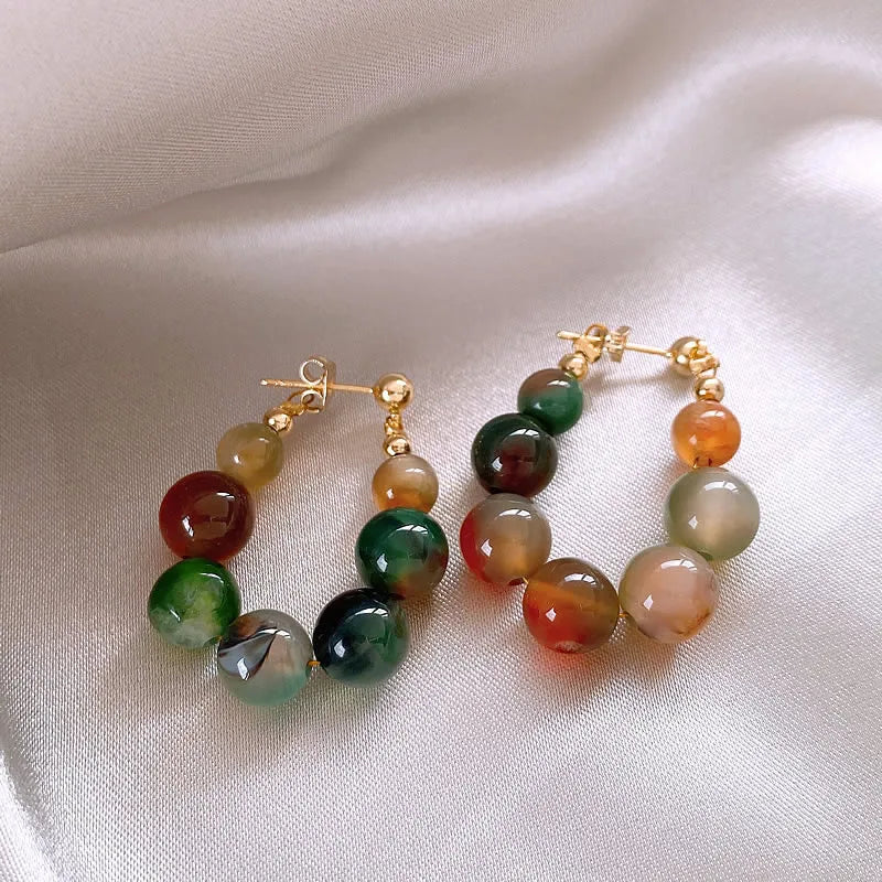 Gold-toned resin beaded drop earrings featuring various shades of green and amber stones.