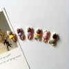 A set of six resin fridge magnets shaped like small, stylized figures in various colors and patterns.