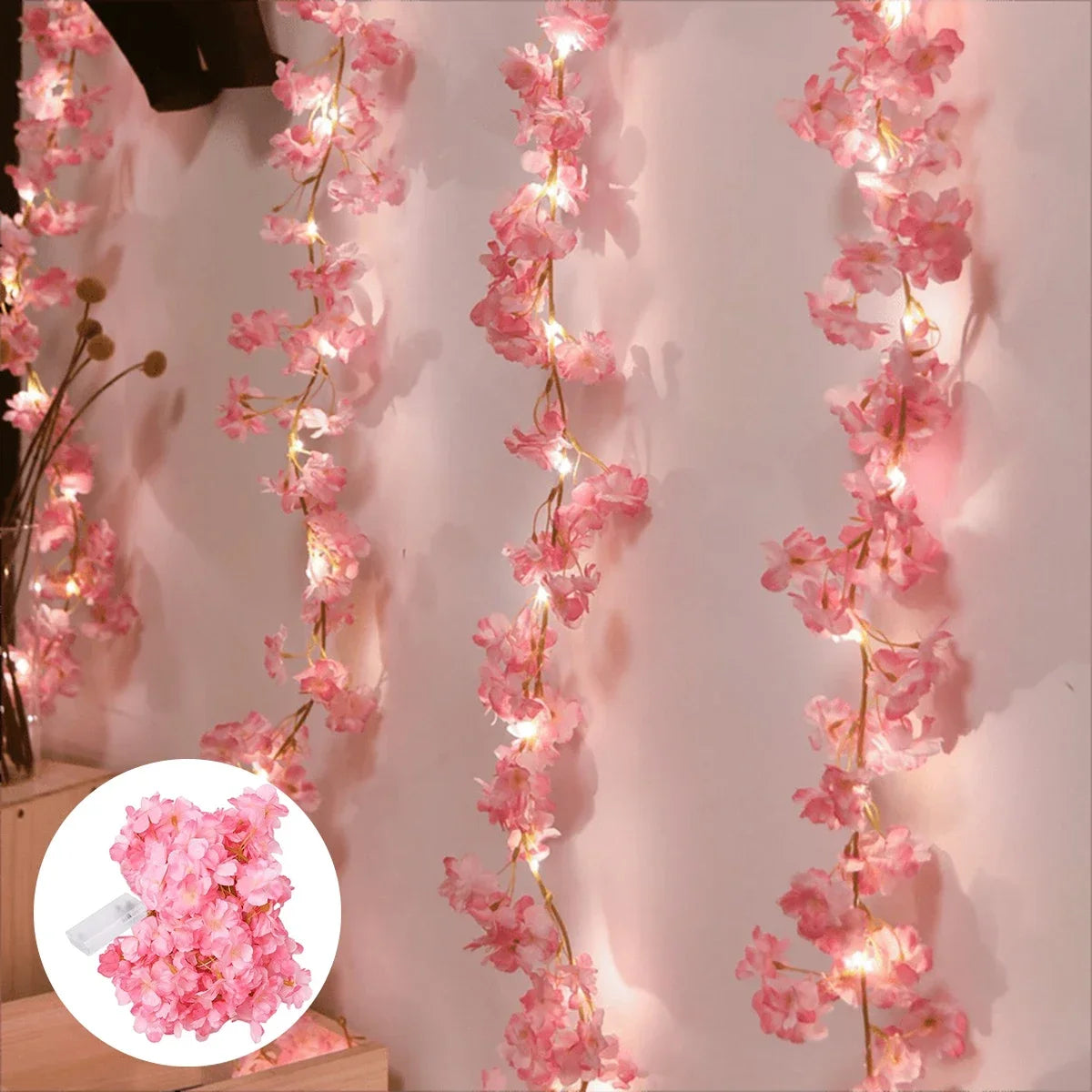Pink cherry blossom string lights garland draped vertically on a white wall.