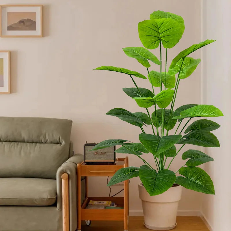 A large, lush artificial green tree with broad leaves in a beige pot displayed indoors.