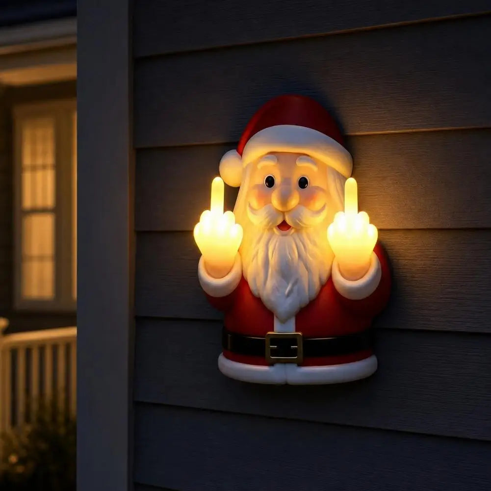 A glowing Santa Claus night light depicting a bearded man in a red suit making a middle finger gesture on a wooden siding.