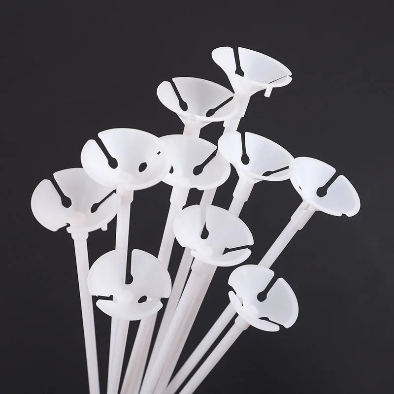 White macaron balloon sticks with holder cups arranged vertically against a dark background