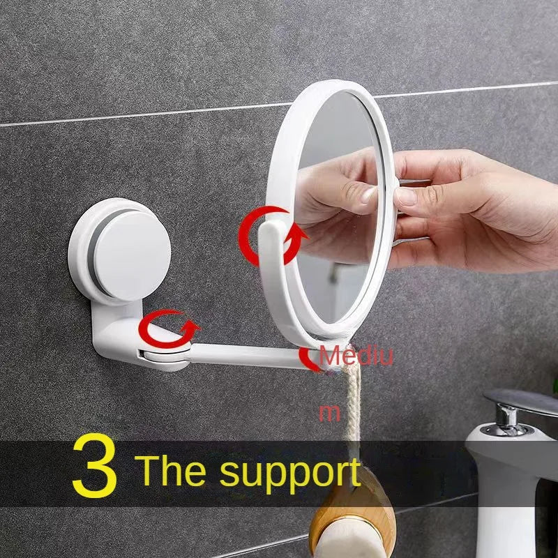 A hand is adjusting a white, round wall-mounted vanity mirror with a rotating mechanism on a gray tiled wall.