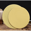 A round, gold-colored cardboard cake board is shown in a slight angle on a wooden surface.