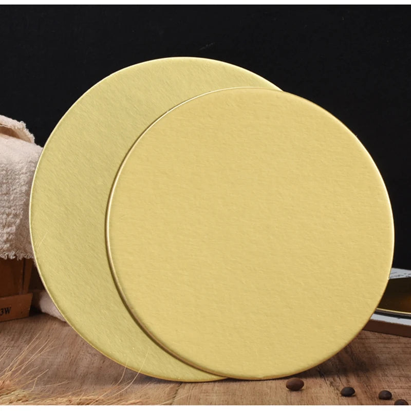 A round, gold-colored cardboard cake board is shown in a slight angle on a wooden surface.