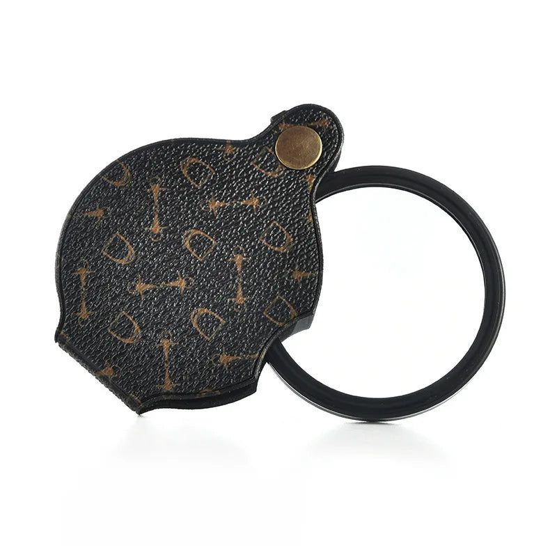 A black pocket magnifier with a leather case and keychain attached.