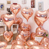 A collection of rose gold heart foil balloons displayed on a white surface.