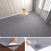 Close-up view of a gray self-adhesive runner rug being applied to a wooden floor.