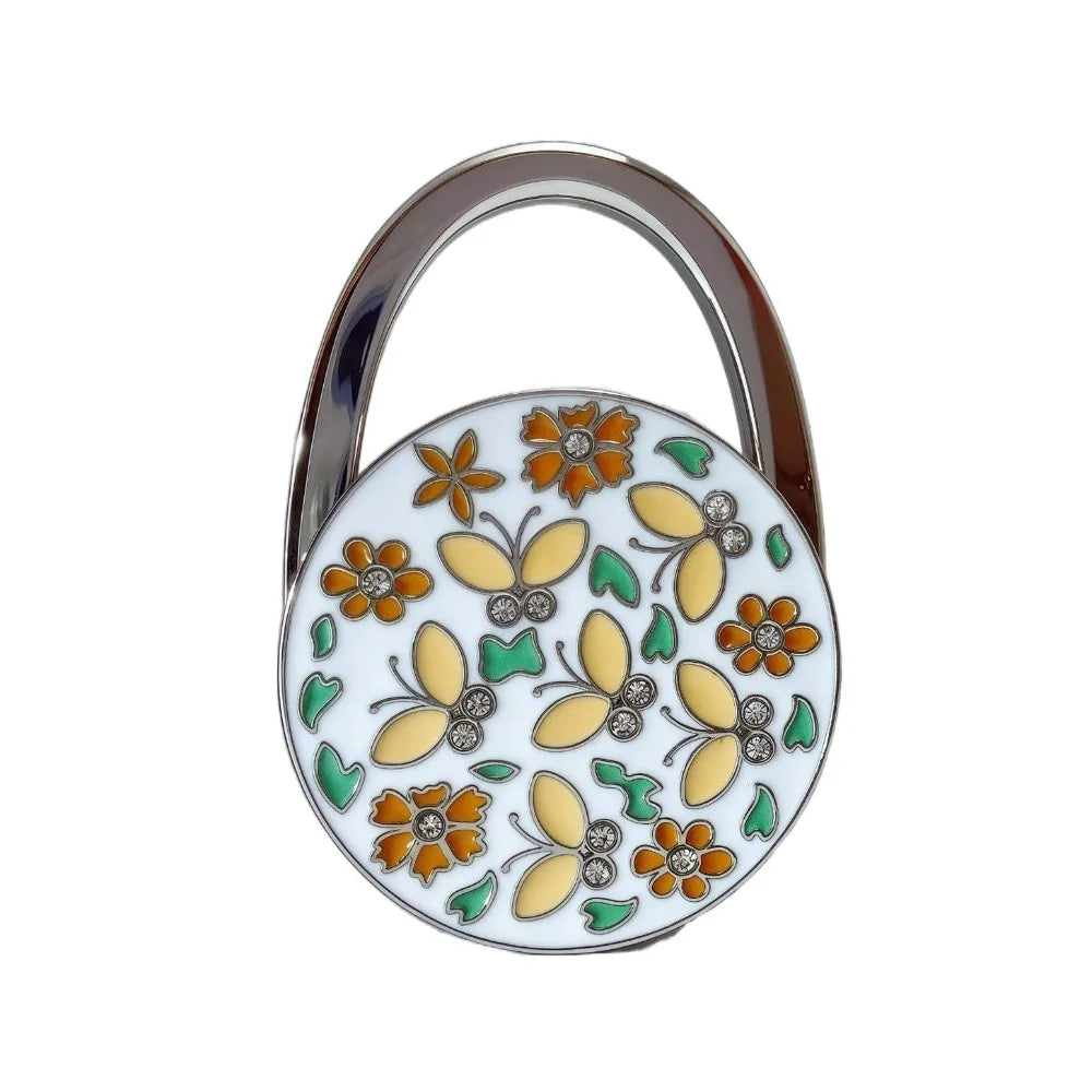 A silver handbag hook with a floral crystal design featuring orange and yellow elements.