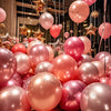 A close-up of pink and gold latex balloons hanging in a party decoration display.