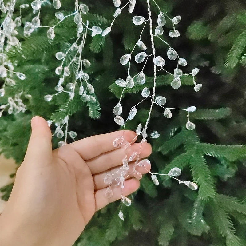 A hand is holding a string of clear acrylic crystal pendant drops used for Christmas tree decoration.