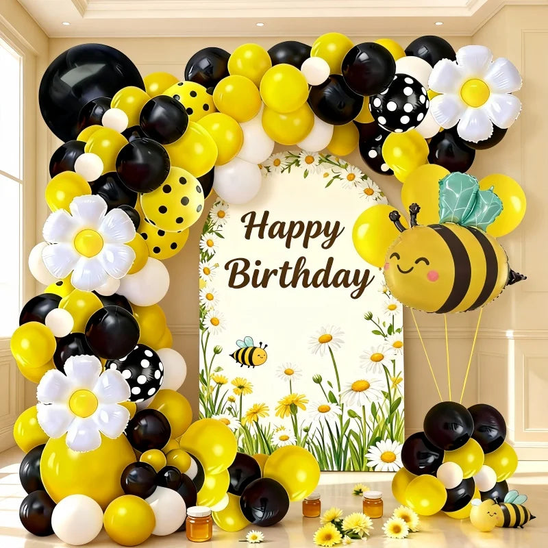A large balloon arch set featuring yellow, black, and white balloons shaped like bees and daisies.