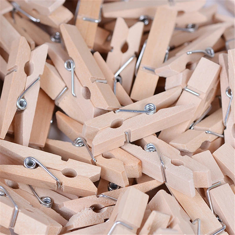 A pile of natural wooden mini clothespins with silver wire clips for crafts and decor.