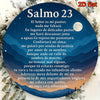A circular piece of 2D flat metal wall art featuring a Spanish Bible verse on a dark blue background surrounded by white flor