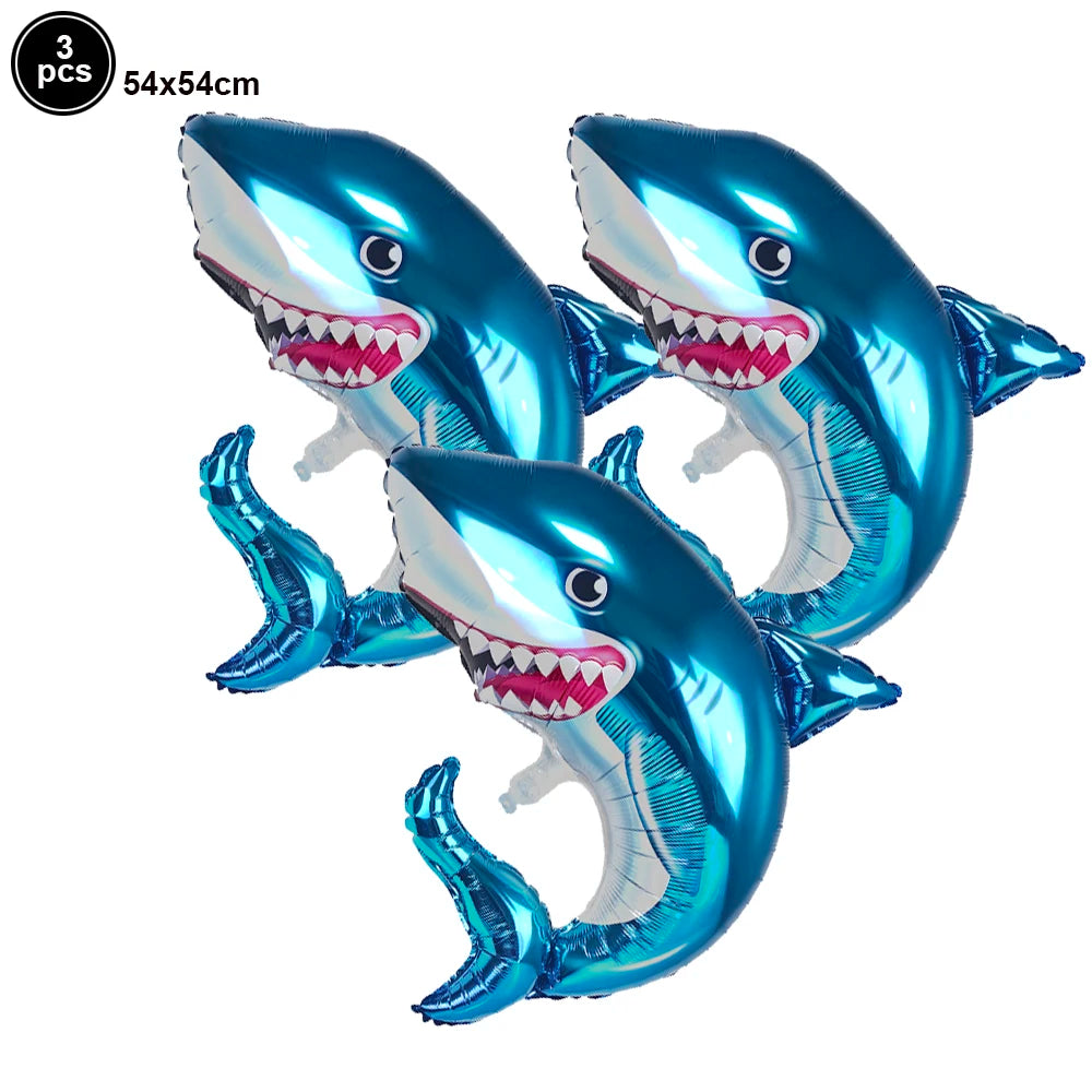 Three blue shark foil balloons with open mouths and teeth for an ocean-themed party decoration