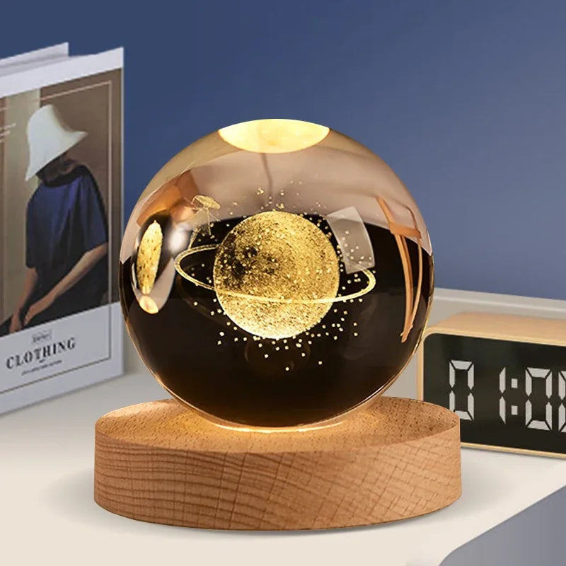 A spherical glass decoration with a gold glitter planet inside, resting on a wooden base.
