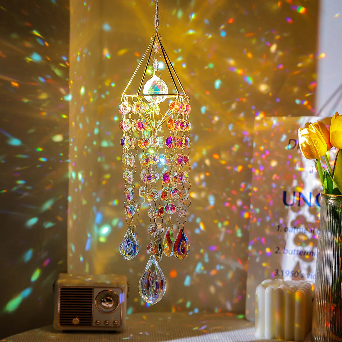A hanging crystal rainbow wind chime decor with multiple glass strands catching light against a golden background.