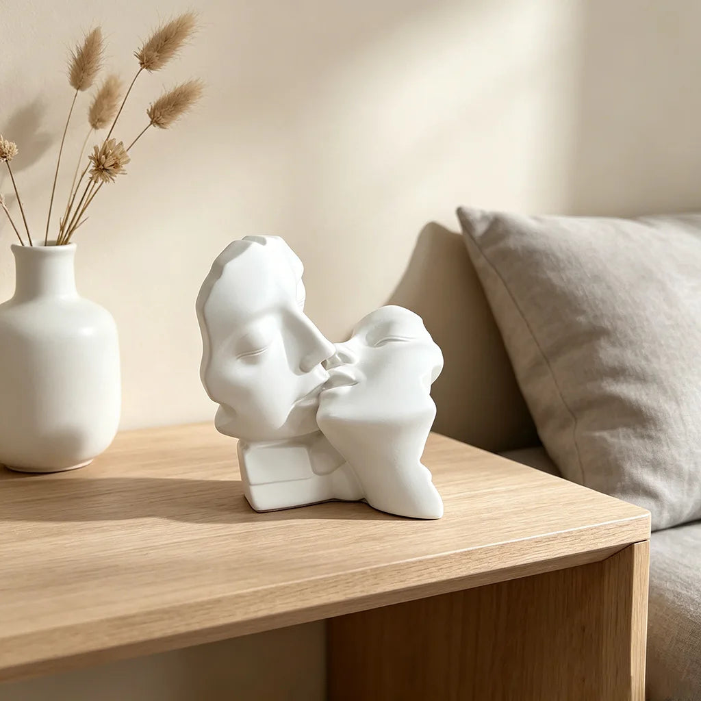 A white resin sculpture depicting an abstract kissing couple resting on a wooden table.