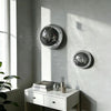 Boule disco en verre miroir argenté, décoration murale accrochée à un mur gris clair près d'une fenêtre.
