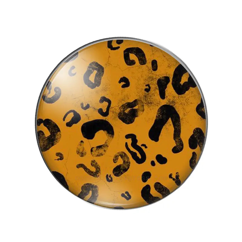 A round glass cabochon with a yellow and black leopard print design.