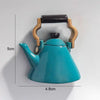 A teal ceramic teapot with a wooden handle and spout, part of a fruit fridge magnet set.