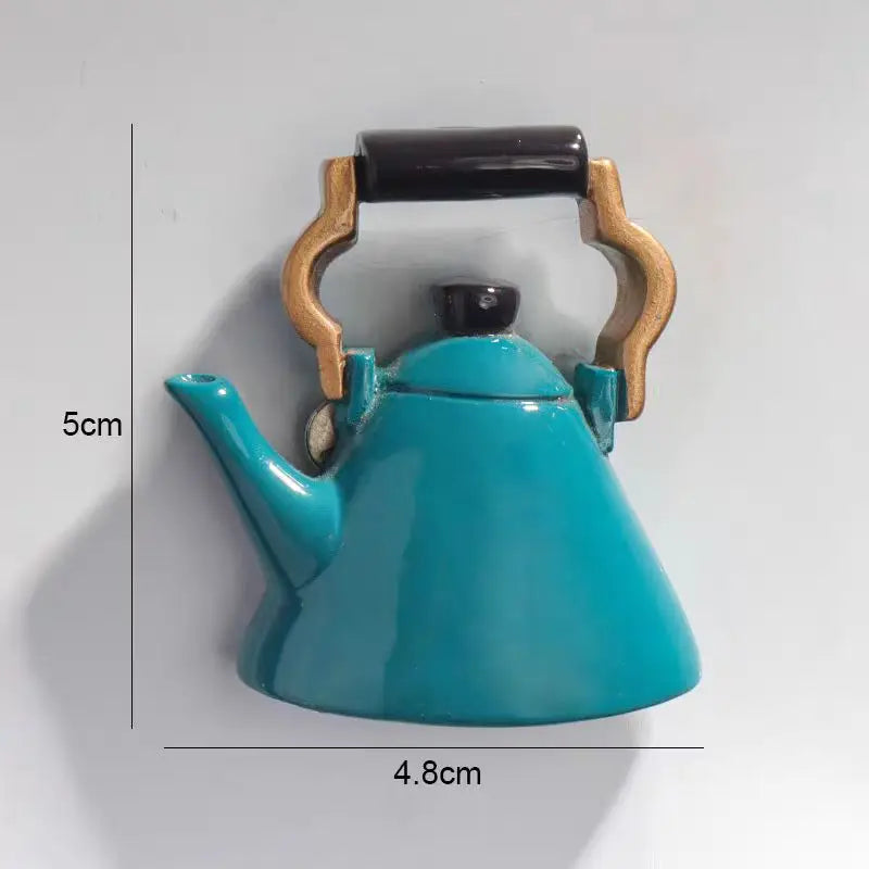 A teal ceramic teapot with a wooden handle and spout, part of a fruit fridge magnet set.