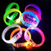 A collection of ten glowing LED flash bracelets in various colors including green, yellow, blue, and pink on a dark backgroun