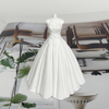 A white silicone mold of a wedding dress is displayed on a surface next to greenery.