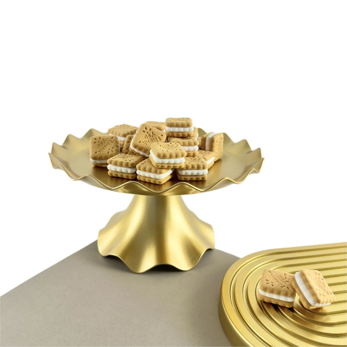 A golden cake stand holds several rectangular cookies on a neutral surface.