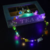 A glowing flower wreath headband with ten LEDs rests on a teal box featuring the word TEA.