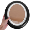 A hand holds an elegant oval wooden wall photo frame with a light brown insert.