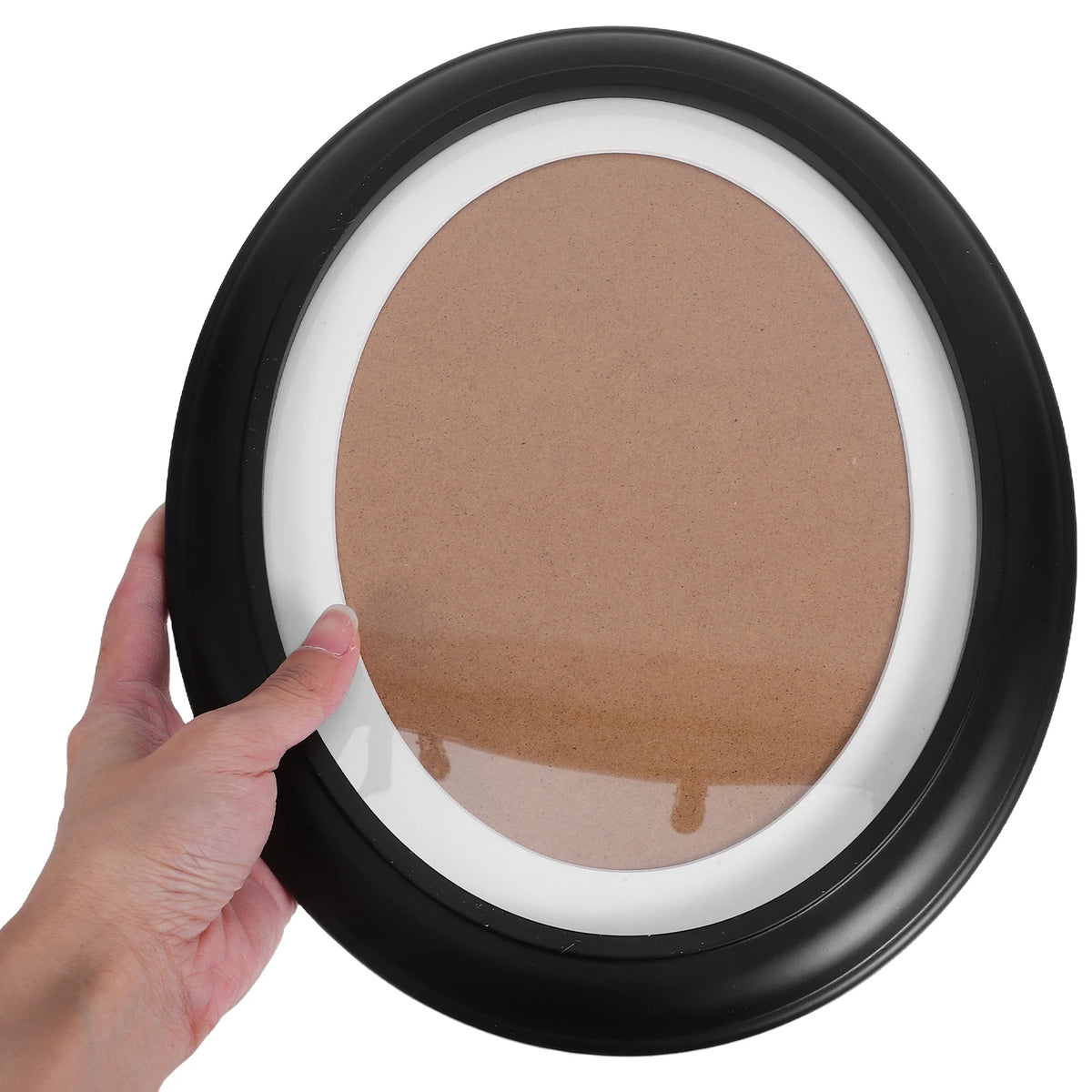 A hand holds an elegant oval wooden wall photo frame with a light brown insert.