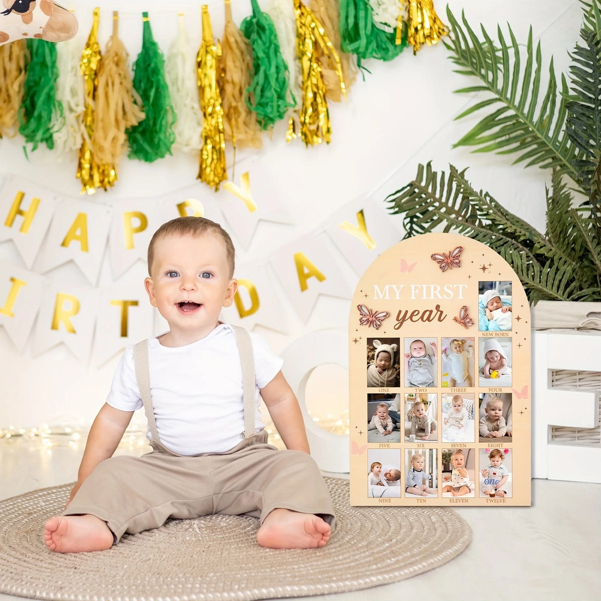 A baby sitting on a mat in front of a milestone board decorated with wooden photo frames and greenery.