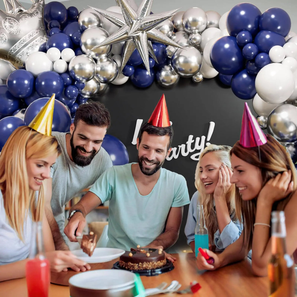 A group of friends celebrating with a navy blue and silver balloon garland arch kit.